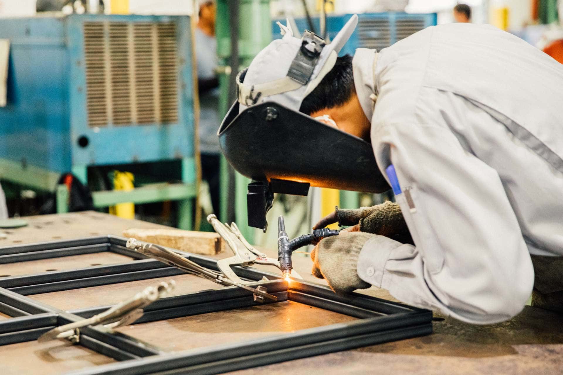 industrial worker in manufacturing plant grinding to finish a metal pipe,industrial worker at the factory welding closeup